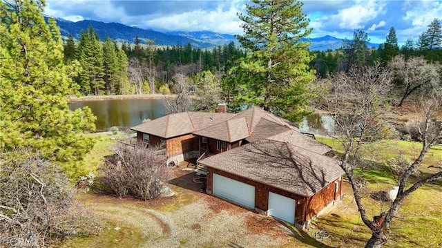 drone / aerial view featuring a view of trees and a water and mountain view