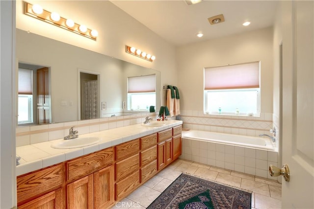 bathroom featuring double vanity, tile patterned flooring, tiled bath, and a sink