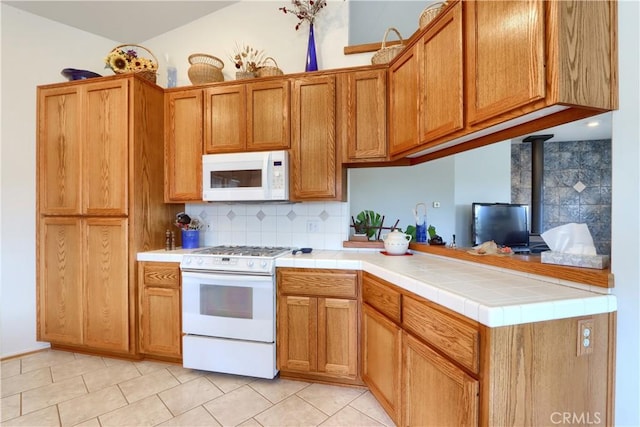 kitchen with tasteful backsplash, white appliances, brown cabinetry, and a wood stove