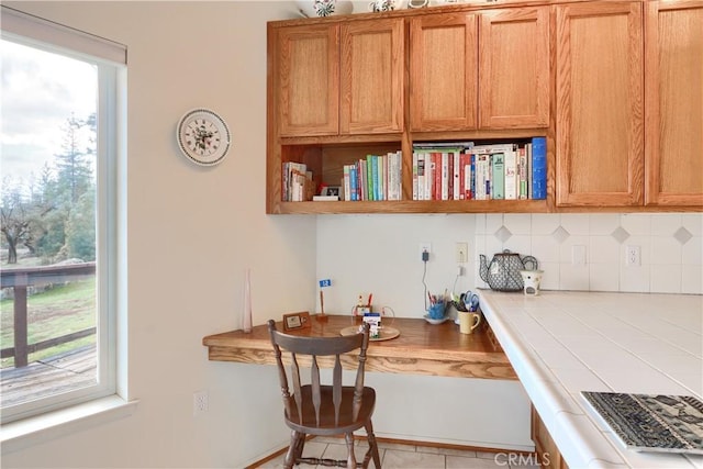 kitchen featuring decorative backsplash, open shelves, tile countertops, and a wealth of natural light