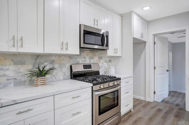 kitchen featuring light wood finished floors, white cabinetry, stainless steel appliances, and light stone countertops