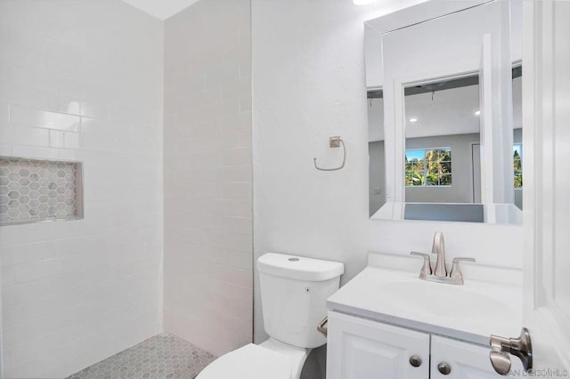 bathroom featuring toilet, vanity, and a tile shower