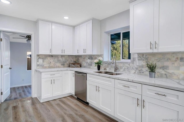 kitchen with white cabinets, stainless steel dishwasher, light wood-style flooring, and a sink