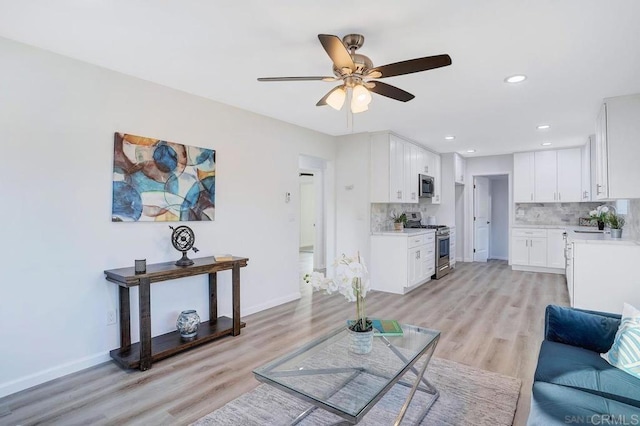 living room featuring light wood-style flooring, recessed lighting, a ceiling fan, and baseboards