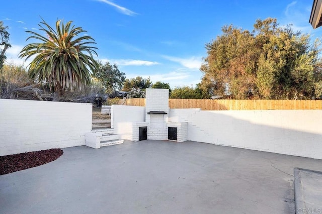 view of patio featuring a fireplace and a fenced backyard