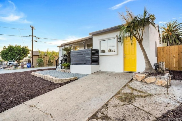 exterior space featuring stucco siding and fence