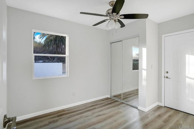 unfurnished bedroom with a closet, baseboards, wood finished floors, and a ceiling fan