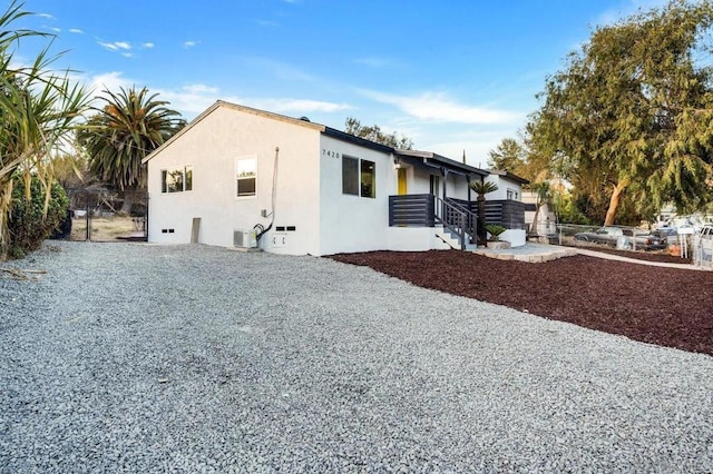 view of side of home featuring stucco siding and fence