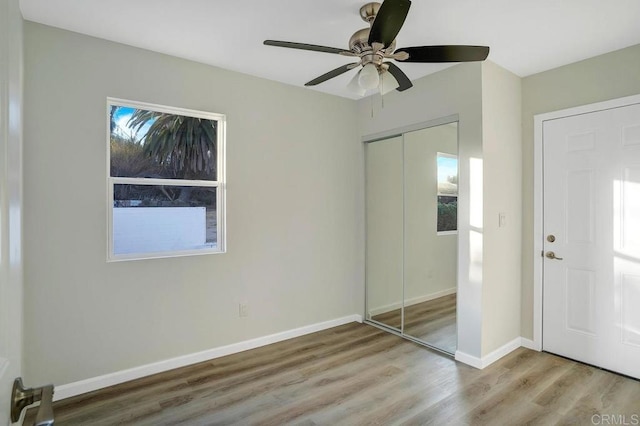 unfurnished bedroom featuring a closet, ceiling fan, baseboards, and wood finished floors