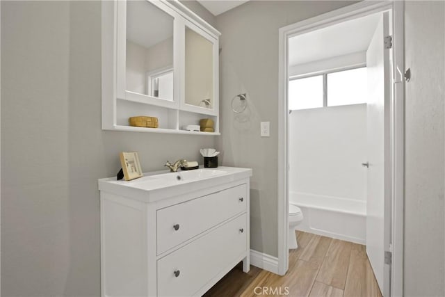 full bathroom featuring a bath, toilet, vanity, and wood tiled floor