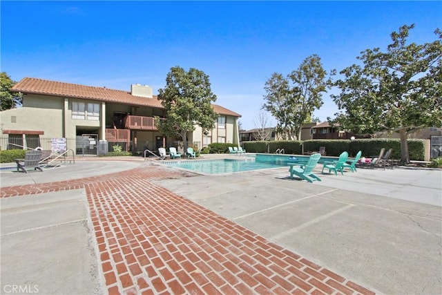 pool with a patio and fence