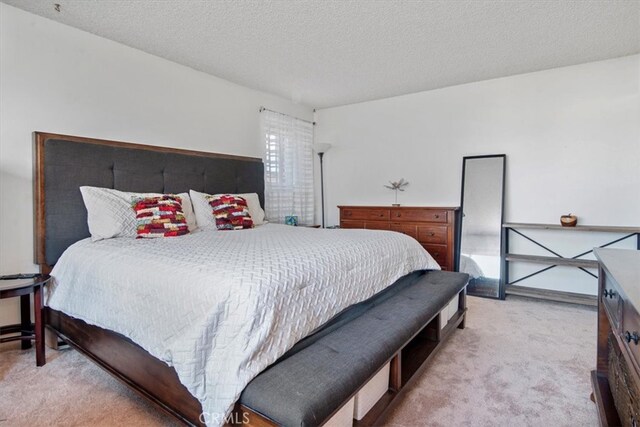 bedroom featuring light carpet and a textured ceiling