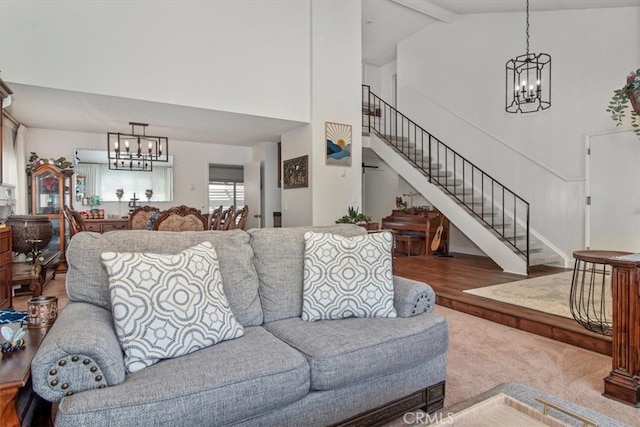 living room featuring stairway, high vaulted ceiling, an inviting chandelier, and beamed ceiling