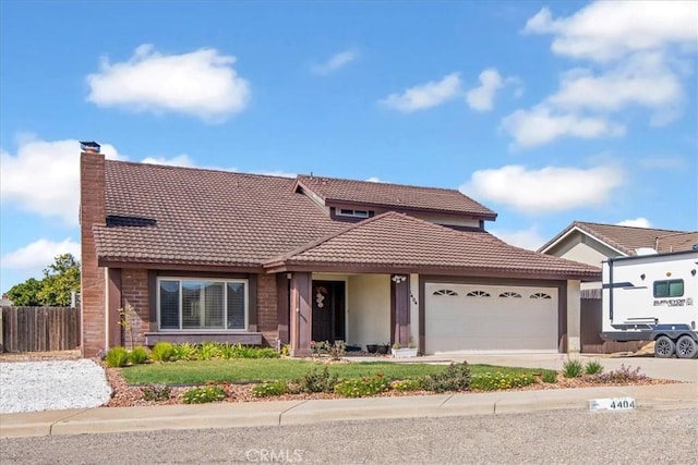 traditional-style home with fence, an attached garage, a chimney, concrete driveway, and a tile roof