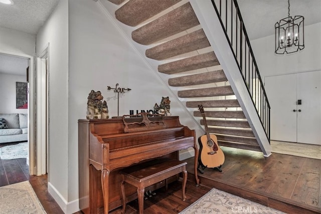 entryway featuring hardwood / wood-style floors, a textured ceiling, stairs, and a chandelier