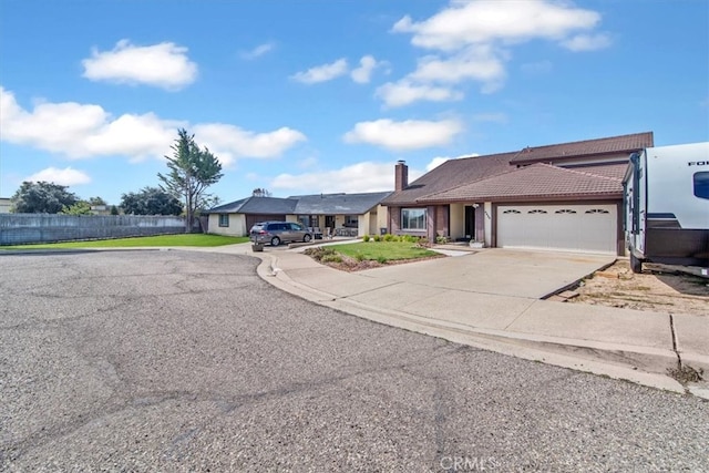 ranch-style home with fence, a chimney, concrete driveway, a garage, and a tile roof