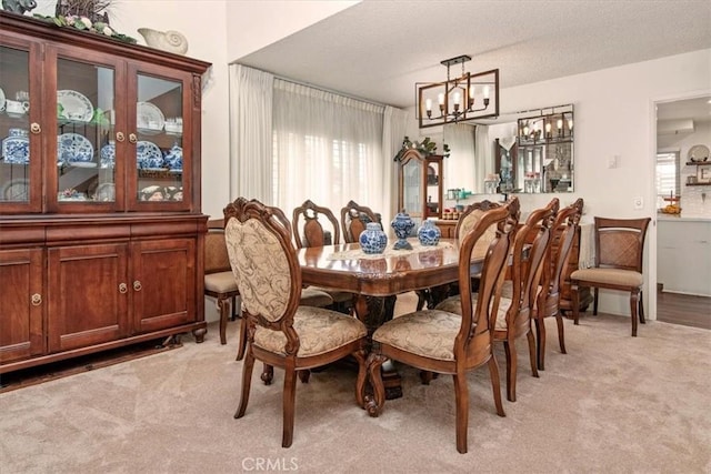 dining area featuring light carpet, a textured ceiling, and an inviting chandelier