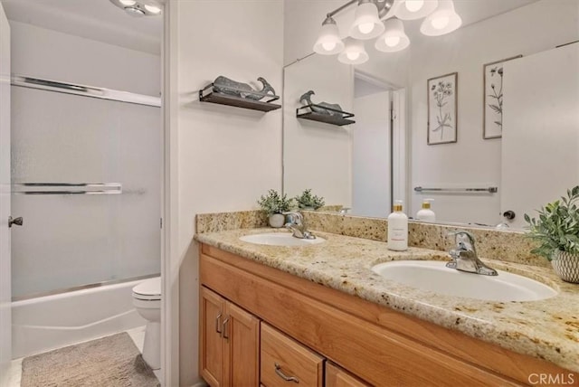 full bath featuring double vanity, toilet, bath / shower combo with glass door, and a sink