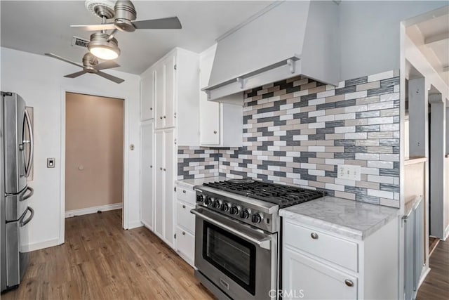 kitchen featuring tasteful backsplash, white cabinets, appliances with stainless steel finishes, and wood finished floors