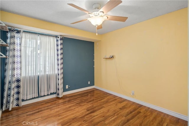 spare room featuring ceiling fan, a textured ceiling, baseboards, and wood finished floors