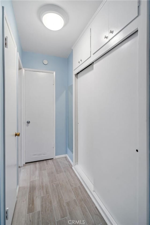 hallway featuring light wood-style flooring and baseboards