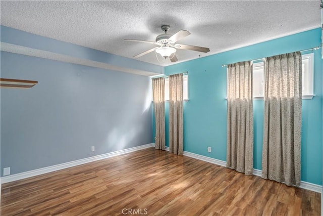 empty room with baseboards, a textured ceiling, wood finished floors, and a ceiling fan