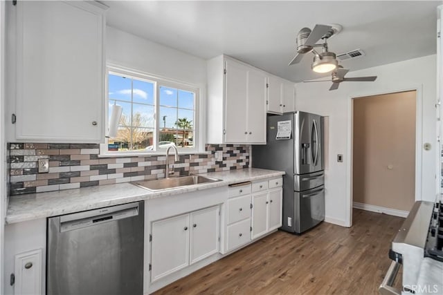 kitchen with decorative backsplash, white cabinets, stainless steel appliances, and a sink