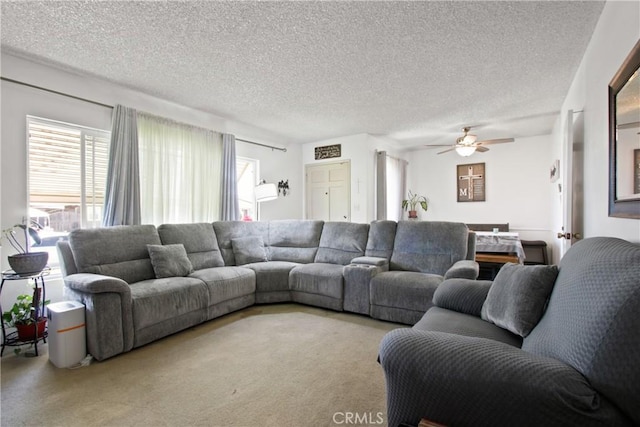 living room featuring ceiling fan, carpet flooring, and a textured ceiling