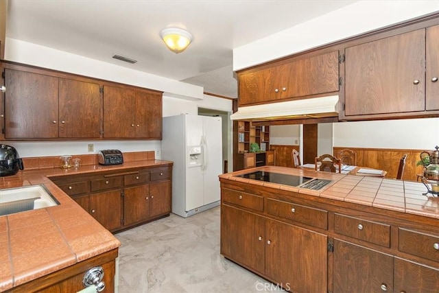 kitchen featuring tile countertops, visible vents, white fridge with ice dispenser, black electric stovetop, and marble finish floor