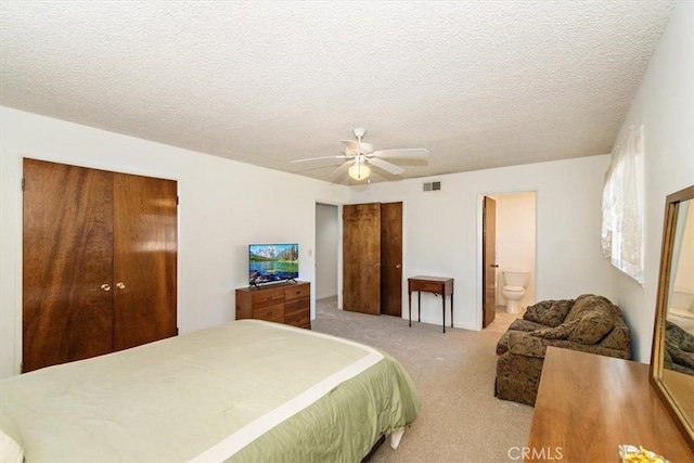 bedroom featuring visible vents, ceiling fan, carpet, multiple closets, and a textured ceiling