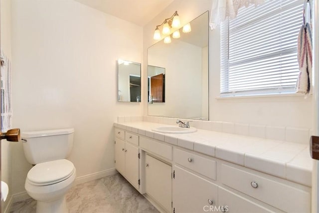 bathroom with baseboards, toilet, marble finish floor, and vanity