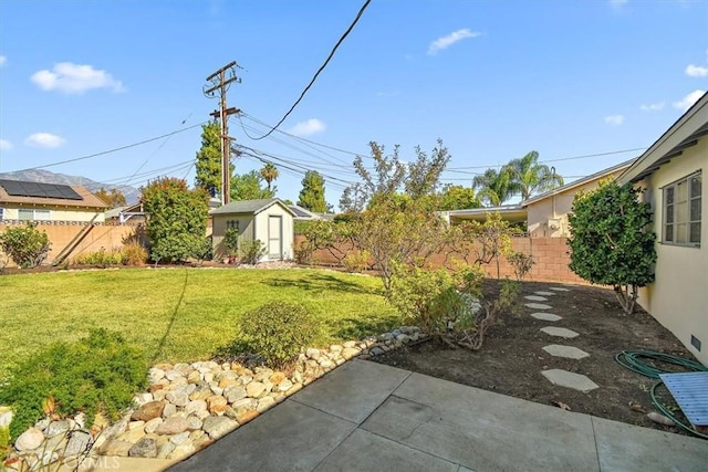 view of yard with a patio, a fenced backyard, and an outdoor structure