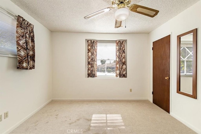 carpeted spare room featuring a ceiling fan, baseboards, and a textured ceiling