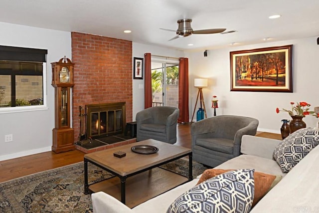 living area with recessed lighting, a brick fireplace, baseboards, and wood finished floors