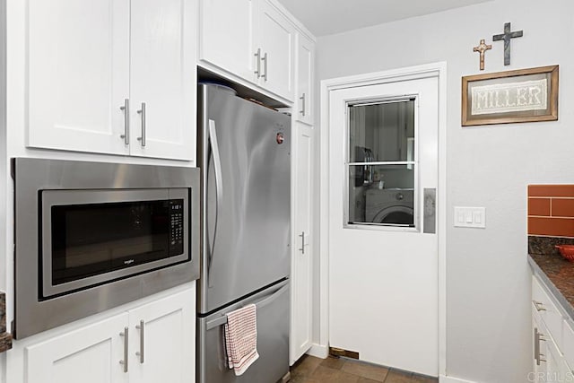 kitchen featuring washer / clothes dryer, appliances with stainless steel finishes, and white cabinetry