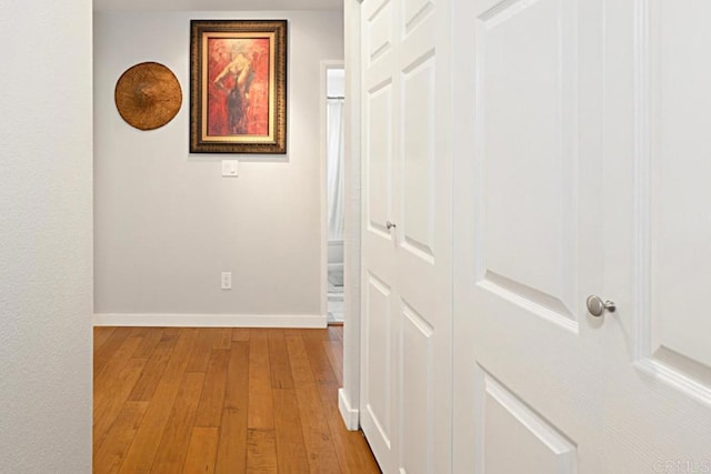 hall featuring light wood-type flooring and baseboards