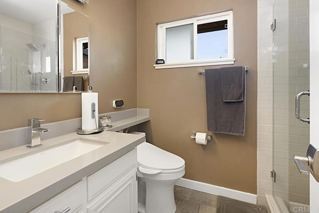 bathroom with a stall shower, toilet, vanity, and baseboards