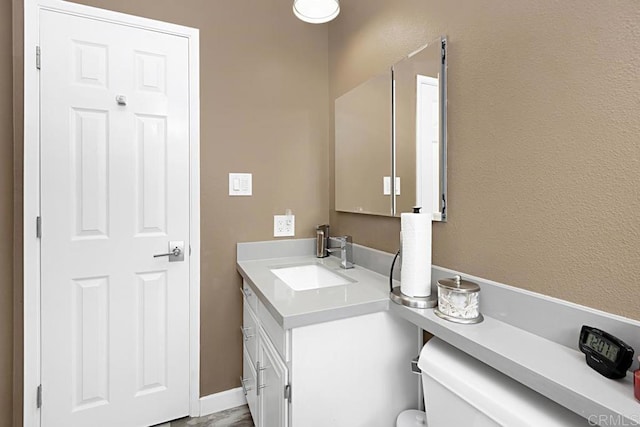 half bathroom featuring baseboards and vanity