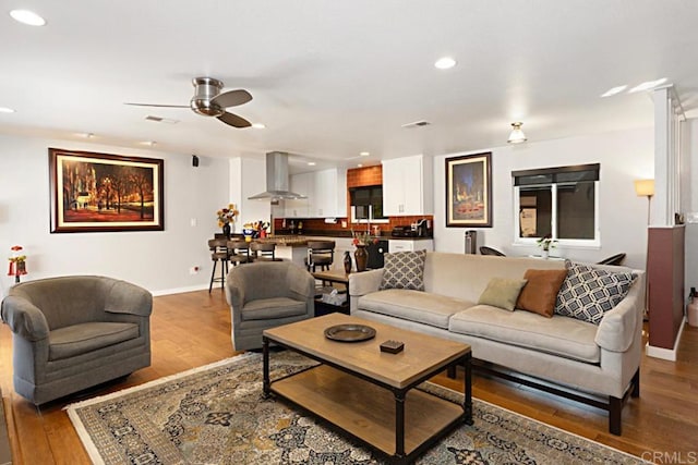 living room featuring recessed lighting, visible vents, baseboards, and wood finished floors