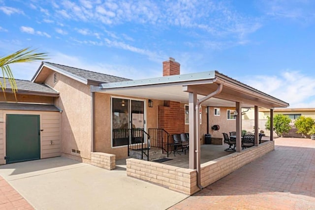 back of property with a patio, stucco siding, and a chimney