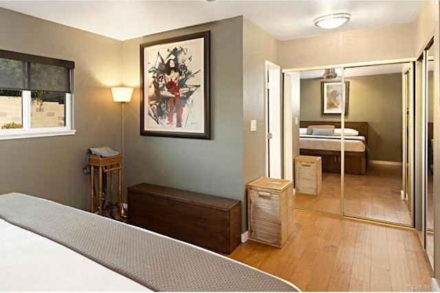 bedroom with a closet, light wood-style flooring, and baseboards