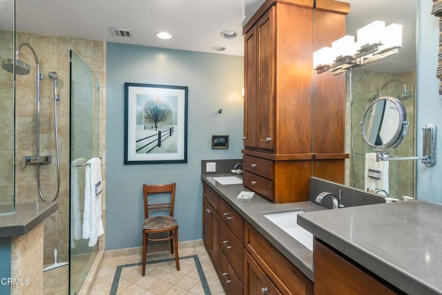 bathroom with baseboards, visible vents, double vanity, a sink, and a shower stall