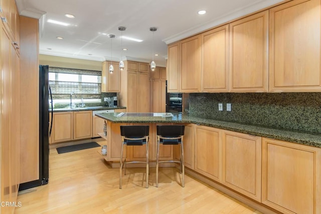 kitchen featuring light wood-style floors, a peninsula, and light brown cabinets