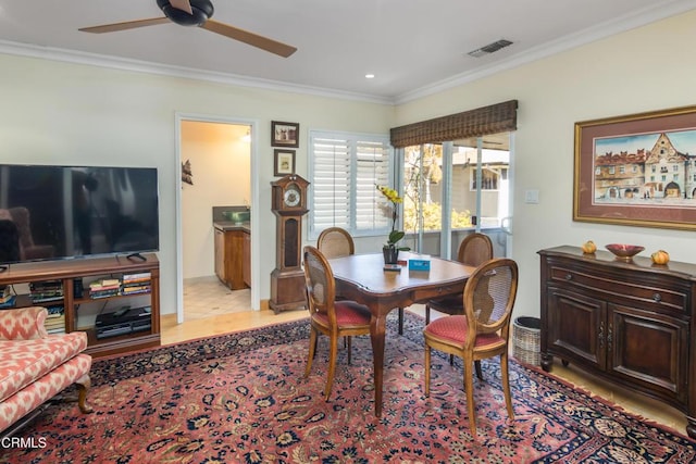 dining space with visible vents, a ceiling fan, and crown molding