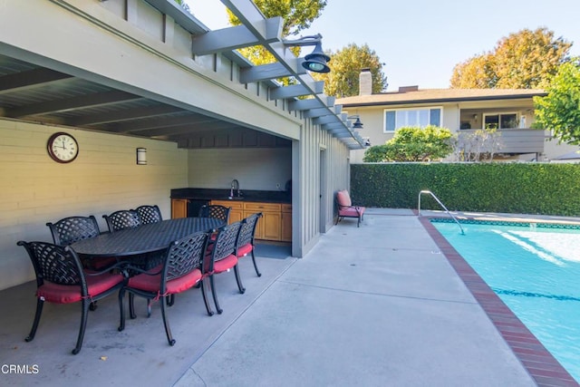 view of pool with a patio area, a fenced in pool, outdoor dining area, and a sink