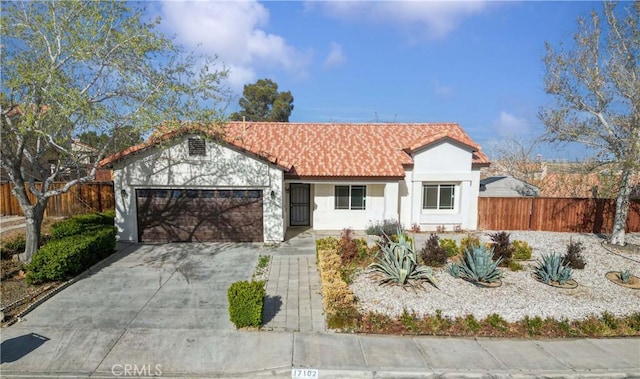 view of front of house with concrete driveway, stucco siding, fence, and an attached garage