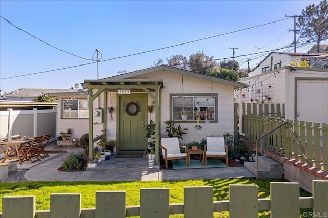 bungalow-style home with an outdoor structure, fence, a front lawn, and a patio area