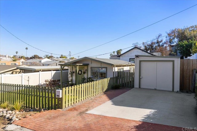 bungalow featuring a fenced front yard, a storage unit, an outbuilding, and a front yard