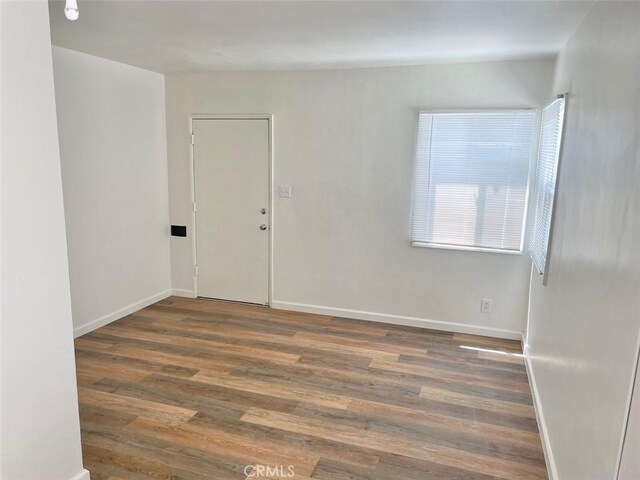 unfurnished room with baseboards and wood finished floors