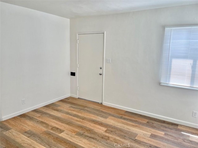 spare room with baseboards and wood finished floors